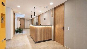 Zona de recepción de hotel con un mostrador de madera, una recepción y una puerta con un letrero de número.