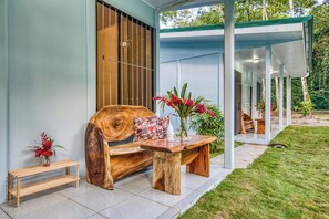 A wooden bench with a cushion and a small table with a vase of flowers. - Kush Villa | Caribbean Hideaway & Pool (Puerto Viejo de Talamanca)
