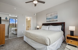A bedroom with a large bed, a ceiling fan, a nightstand with a lamp, a mirror, and a view of the outside. - 2 Bed Gym Pool Cabana Across from Lifetime Fitness 2 Miles to Kierland Commons (Phoenix)