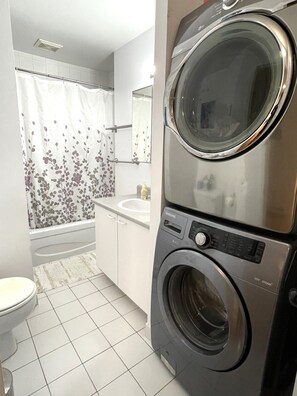 Ein kleines Badezimmer mit Waschmaschine, Toilette und Duschbereich.