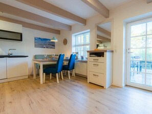 A modern kitchen with a dining area, wooden floors, and a view through a glass door. - Holiday Apartment 5 "grode" (Tating)