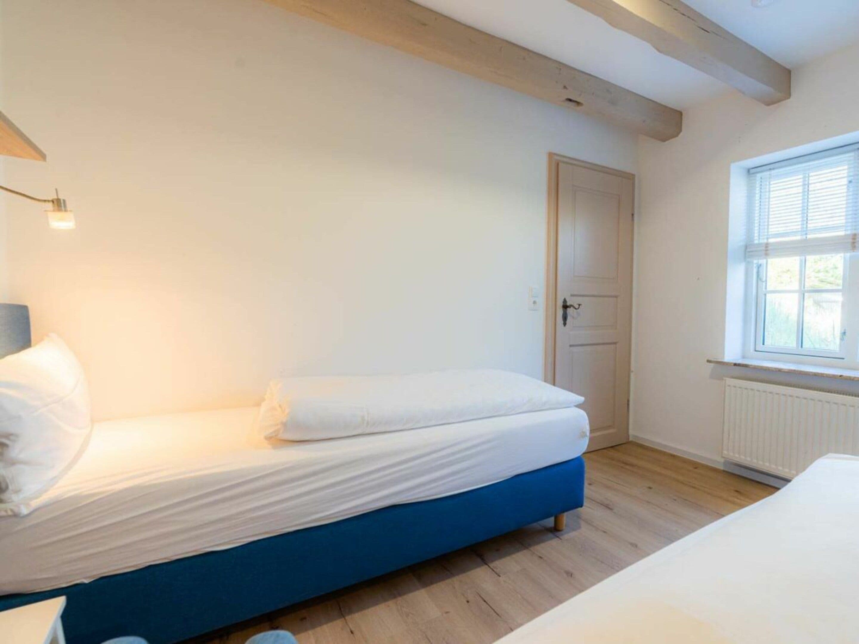 A bedroom with a single bed, a door, a window, and a radiator.