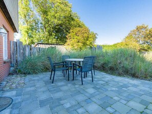 A patio with a table and chairs, surrounded by a brick wall and a wooden fence. - Holiday Apartment 5 "grode" (Tating)