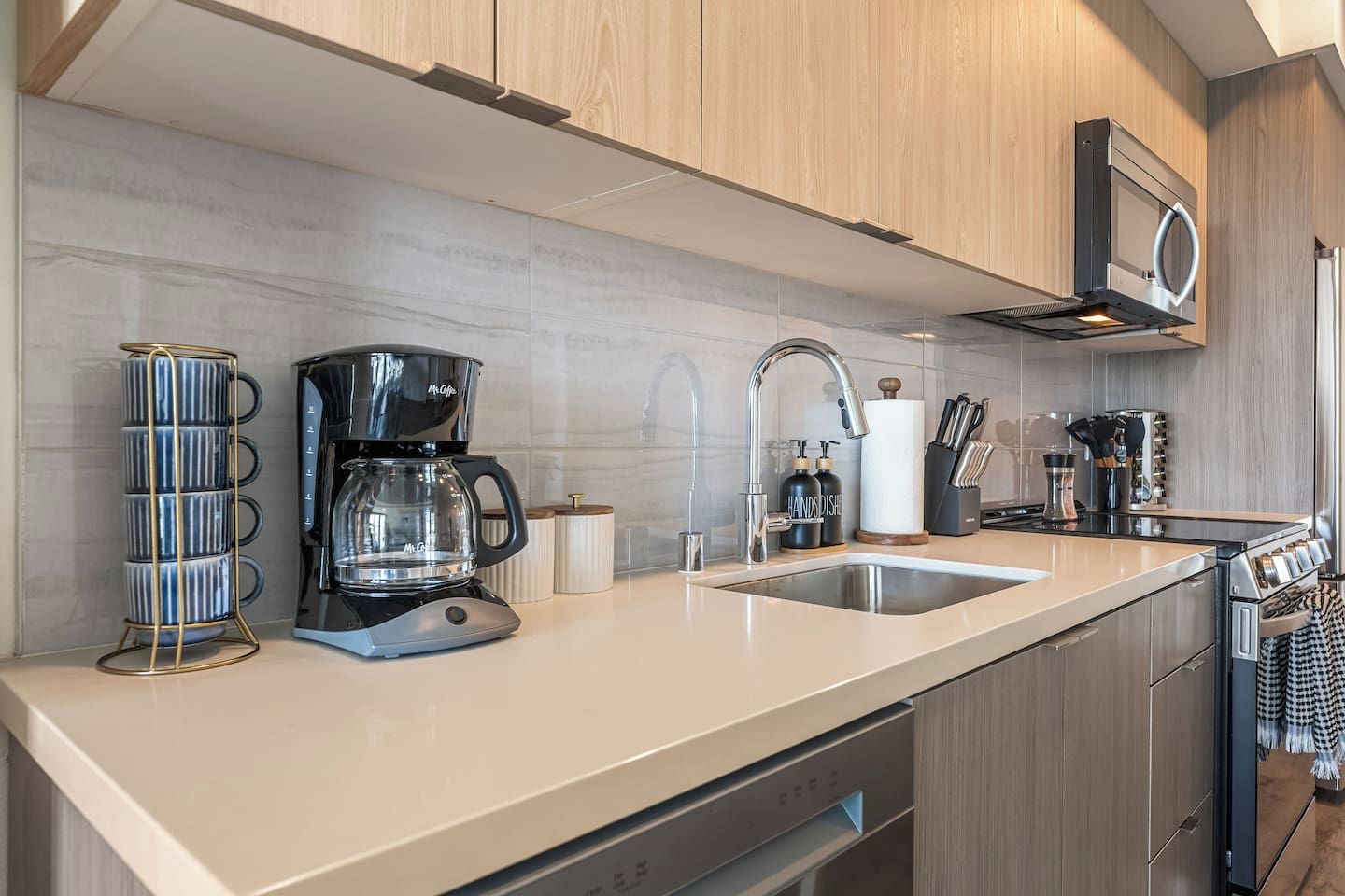A modern kitchen with a coffee maker, sink, and a microwave.