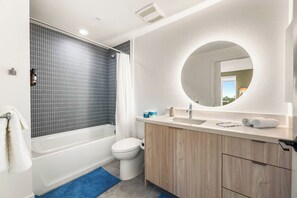 Uma casa de banho moderna com banheira, sanita e lavatório com espelho.