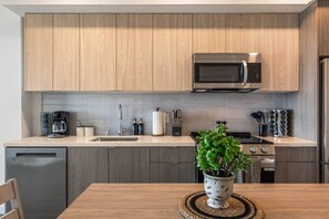 Une cuisine moderne avec des meubles en bois, un four à micro-ondes en acier inoxydable et une cuisinière.