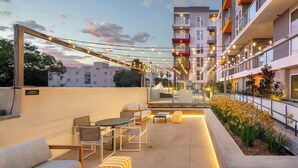 An outdoor patio area with seating arrangements, string lights, and a view of the surrounding buildings. - Light-Filled K-town 3BD 3BTH W/Pool, Gym & Parking (Los Angeles)