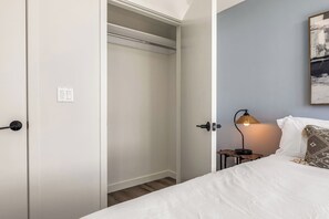 Une chambre à coucher comprenant un lit, une table de chevet, une lampe et une œuvre d’art accrochée au mur.