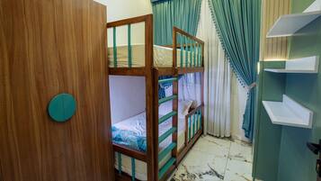 A room with bunk beds, a wardrobe, and a bathroom with a shower.