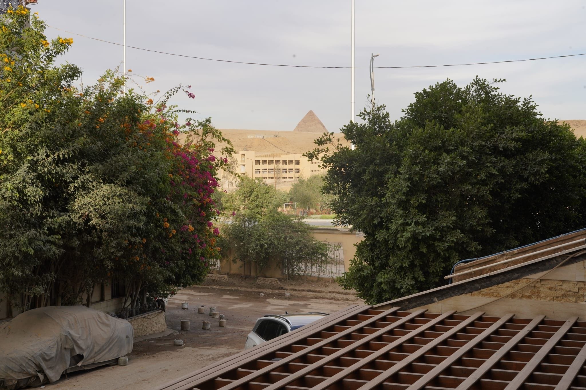 Une vue d’une pyramide et d’un bâtiment à toit plat, entourés d’arbres et recouverts d’une bâche.