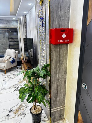 A modern interior with a marble floor, a sofa, a television, and a red first aid box.
