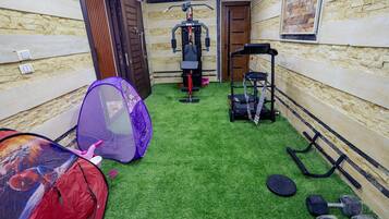 A gym with exercise equipment, a Spider-Man tent, and a small table.