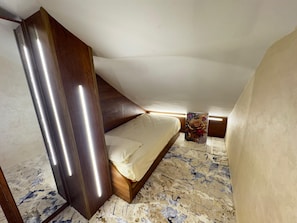Un dormitorio con una cama, cabecera de madera y mesita de noche con un objeto estampado con motivos florales.