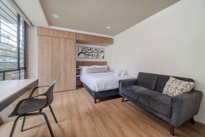 Ein modernes Schlafzimmer mit Bett, Sofa, Schreibtisch und Stuhl.