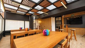 A conference room with a long wooden table, multiple chairs, a projector screen, and a large flat-screen TV. - Apto Moderno 1 hab Bog Sierra Madre (Bogotá)