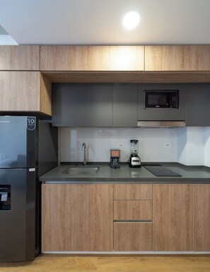 Una cucina moderna dotata di frigorifero, forno a microonde, macchina da caffè e frullatore.