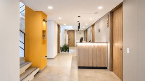 A modern hotel lobby with a reception desk, a staircase, and a plant. - Studio Bogota 1Bed Sierra Madre 306 (Bogotá)