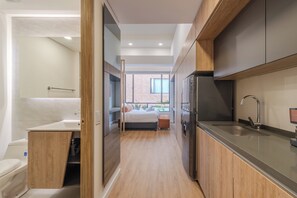 Eine moderne Küche mit Einbaukühlschrank, Spüle und Fenster mit Blick auf ein Backsteingebäude.