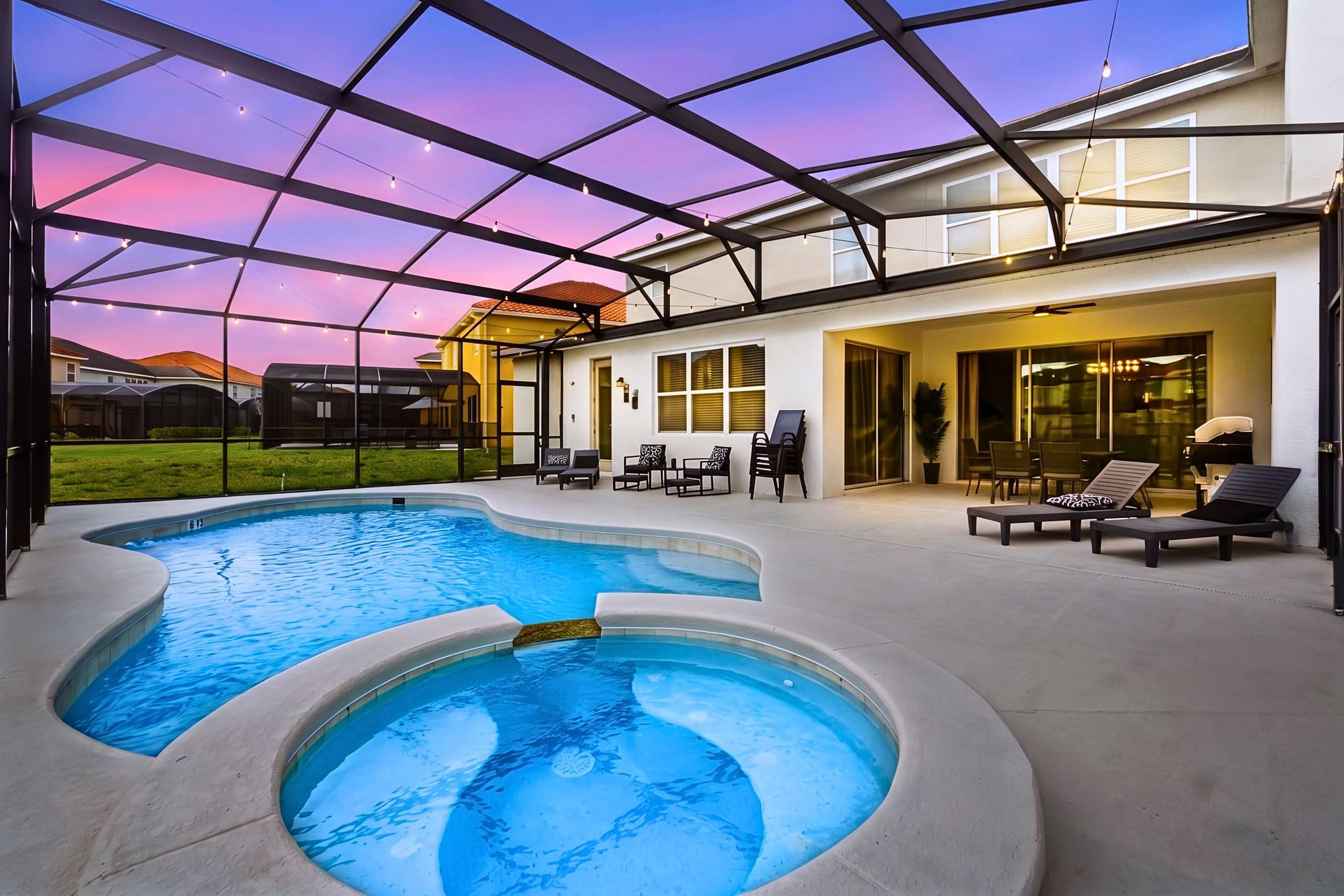 A swimming pool with a glass ceiling, lounge chairs, and a patio area.