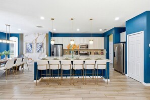 A modern kitchen with a central island, bar stools, and stainless steel appliances. - Grand Villa w Pool, Spa, Games & Theatre near Disney (Davenport)
