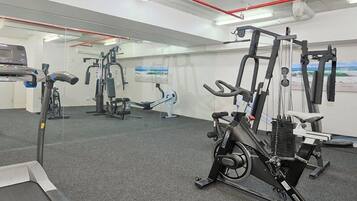 A gym with cardio machines, weightlifting equipment, and a mirrored wall.