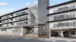 Ein mehrgeschossiges Gebäude mit moderner Architektur, das durch ein markantes vertikales Element und einen überdachten Eingang gekennzeichnet ist.