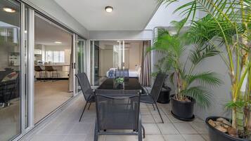 A modern room with a glass partition, a dining table with chairs, and potted plants.