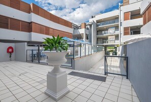 A modern outdoor area with a white planter, a fire hydrant, and a gated entrance. - Unbeatable Convenience, the City on your Doorstep (Fortitude Valley)
