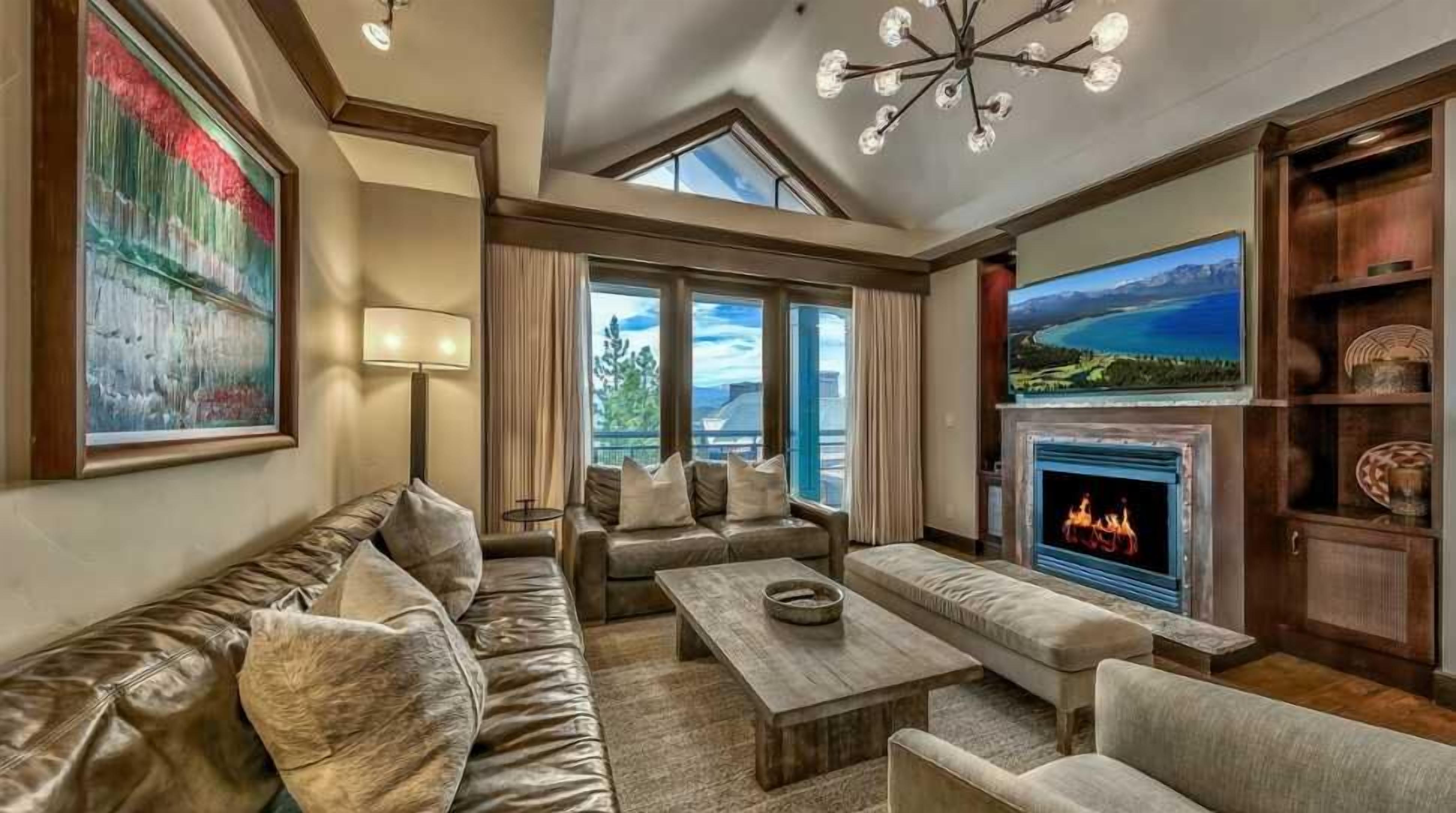 A spacious living room with a fireplace, comfortable seating, and large windows offering a view.
