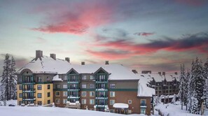 A multi-story hotel with snow-covered roofs and a backdrop of a colorful sky. - Northstar Resort, Mid Mountain, Ski in/Ski Out 4- bedroom Penthouse (Truckee)