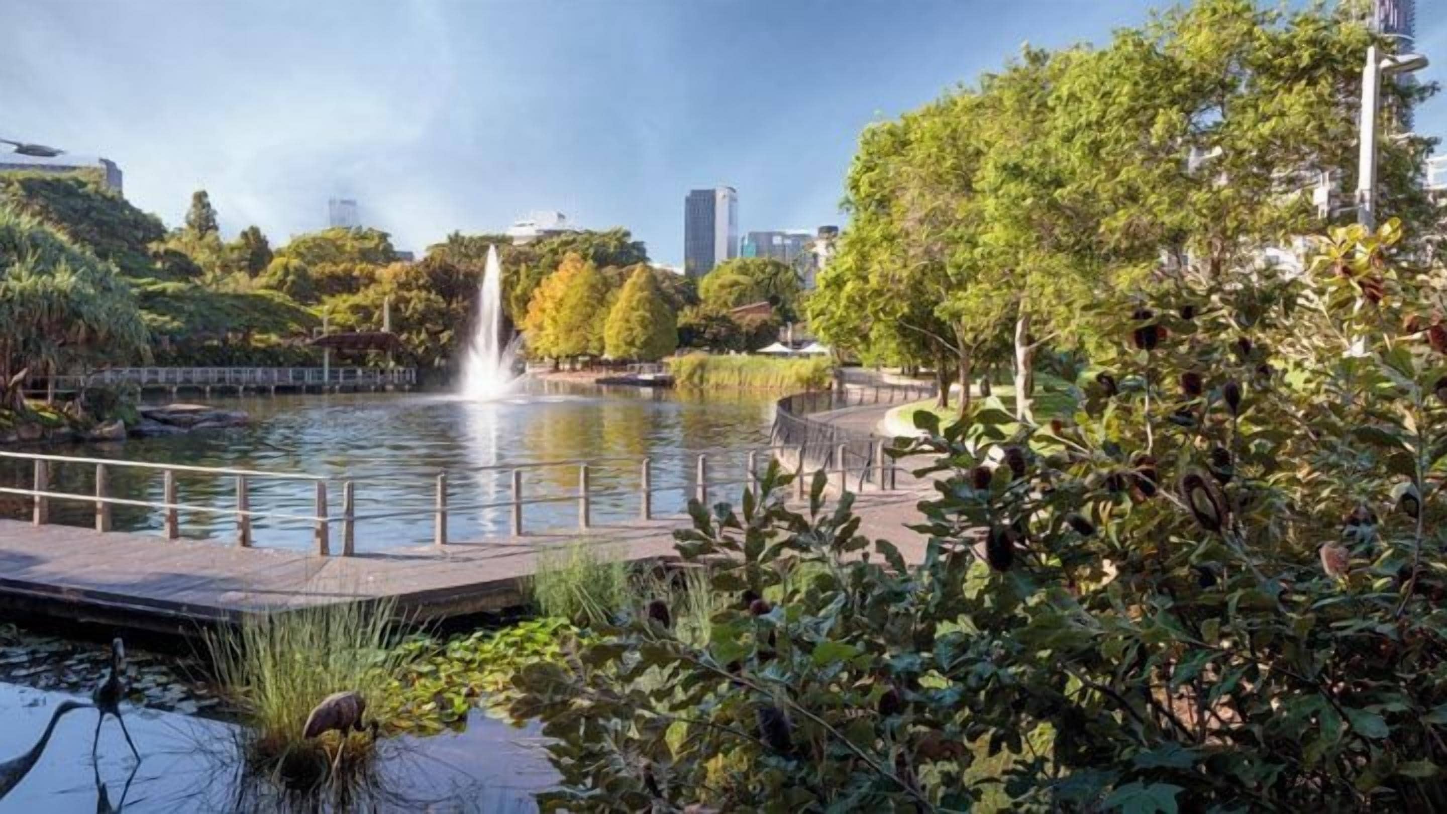 A park with a pond, a fountain, and a bridge.