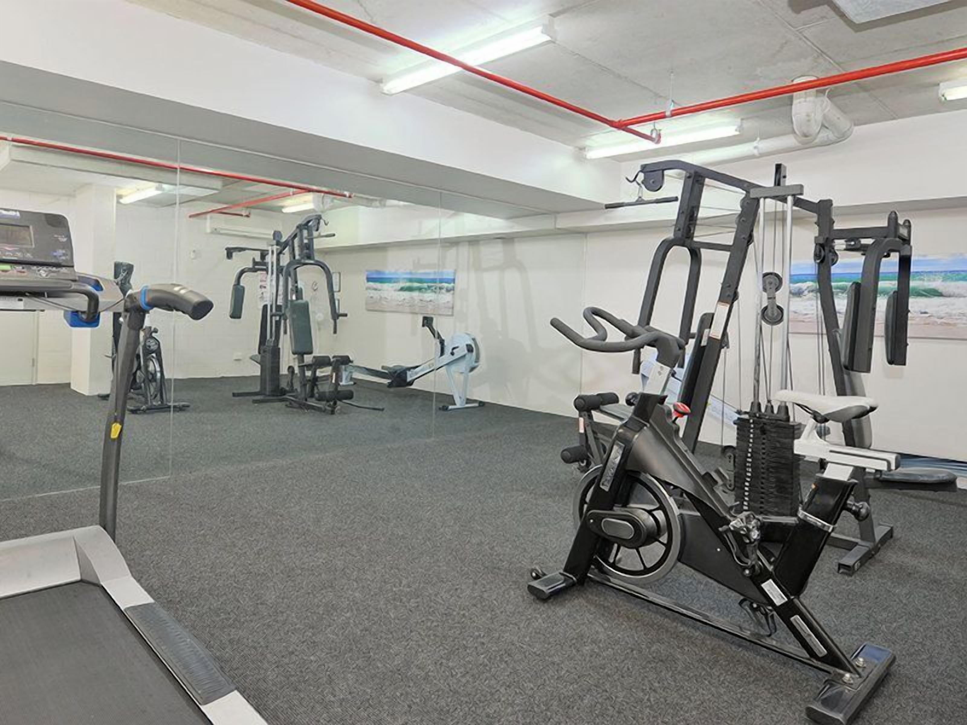 A gym with exercise equipment, a treadmill, and a stationary bike.