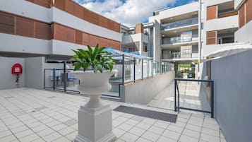 A modern outdoor area with a white planter, a fire hydrant, and a gated entrance.