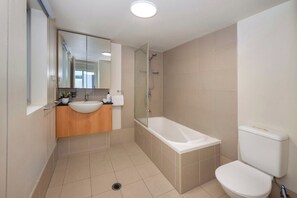 A modern bathroom with a bathtub, toilet, and vanity. - Huge terrace apartment (~150sqm) with free parking (Fortitude Valley)