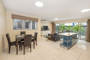A modern living room with a dining area, a sofa, a TV, and a balcony with a view of greenery. - Huge terrace apartment (~150sqm) with free parking (Fortitude Valley)