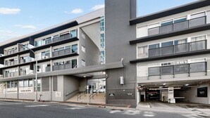 Ein mehrgeschossiges Gebäude mit moderner Architektur, das durch ein markantes vertikales Element und einen überdachten Eingang gekennzeichnet ist.