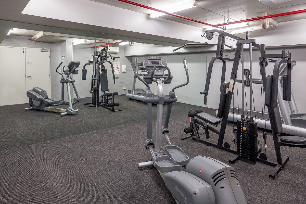 A gym with various exercise equipment including treadmills, elliptical machines, and weight machines.
