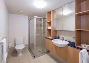 A modern bathroom with a glass-enclosed shower, a white toilet, a wooden vanity with a sink, and a large mirror. - Big & Breezy | Free Parking | Stroll to HSW (Fortitude Valley)