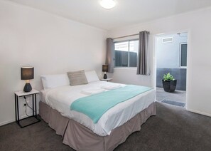 A bedroom with a bed, bedside lamps, a window with curtains, a potted plant, and a view of the outside. - Big & Breezy | Free Parking | Stroll to HSW (Fortitude Valley)