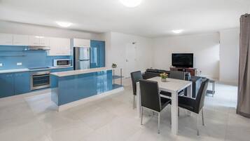 A modern kitchen with blue cabinets, a central island, and a dining area with a table and chairs.
