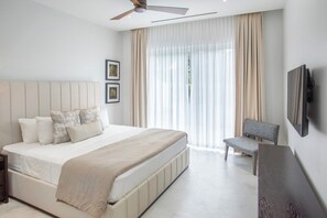 Ein modernes Schlafzimmer mit einem großen Bett, einem flachbildfernseher an der Wand und einem Deckenventilator.