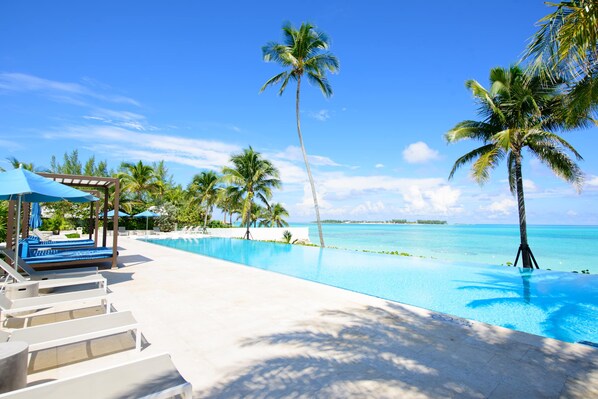 Ein Poolbereich mit Liegestühlen, einer Pergola und Palmen.