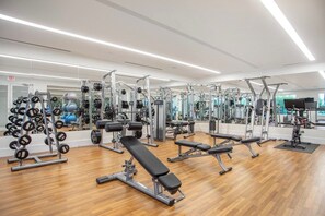 Ett gym med olika typer av träningsutrustning, inklusive styrketräningsmaskiner, lösa vikter och konditionsmaskiner.