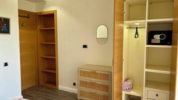 Une chambre à coucher avec une armoire en bois, une table de chevet, un miroir et un petit meuble.