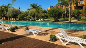 Ein Poolbereich mit Liegestühlen und einer Holzterrasse.