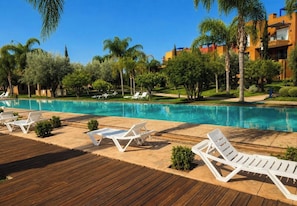 Un espace piscine avec des chaises longues et une terrasse en bois.