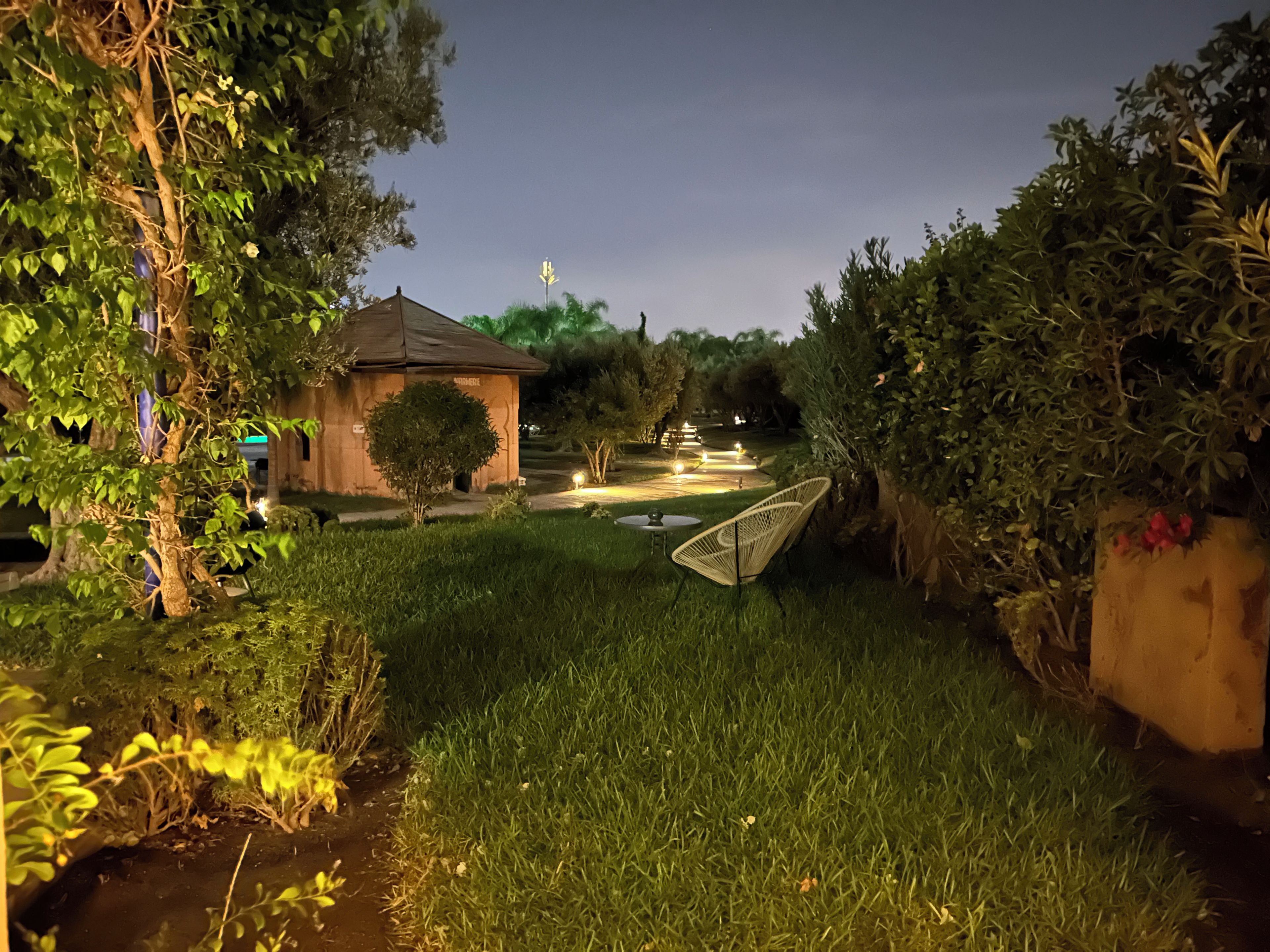 Ein Garten mit einem kleinen Gebäude, einem Weg und einem Stuhl.