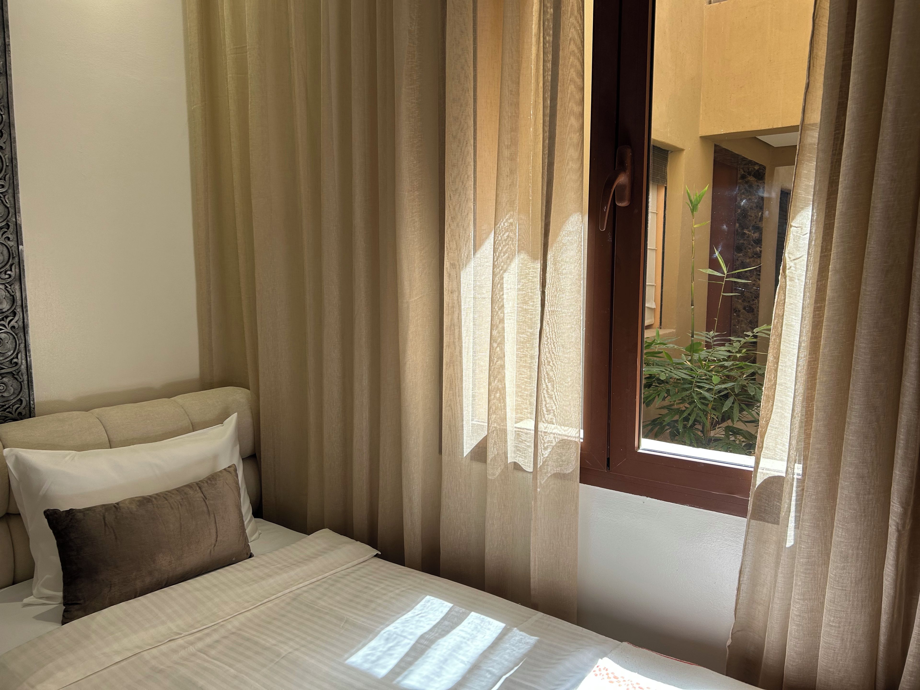 Una habitación de hotel con cama, cortinas y vistas a un patio.