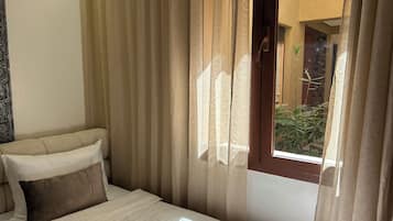 Una habitación de hotel con cama, cortinas y vistas a un patio.