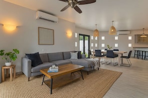 A modern living room with a sofa, coffee table, and dining area. - Marbella lane - Chic Casa with Amazing OceanViews (Cabo San Lucas)